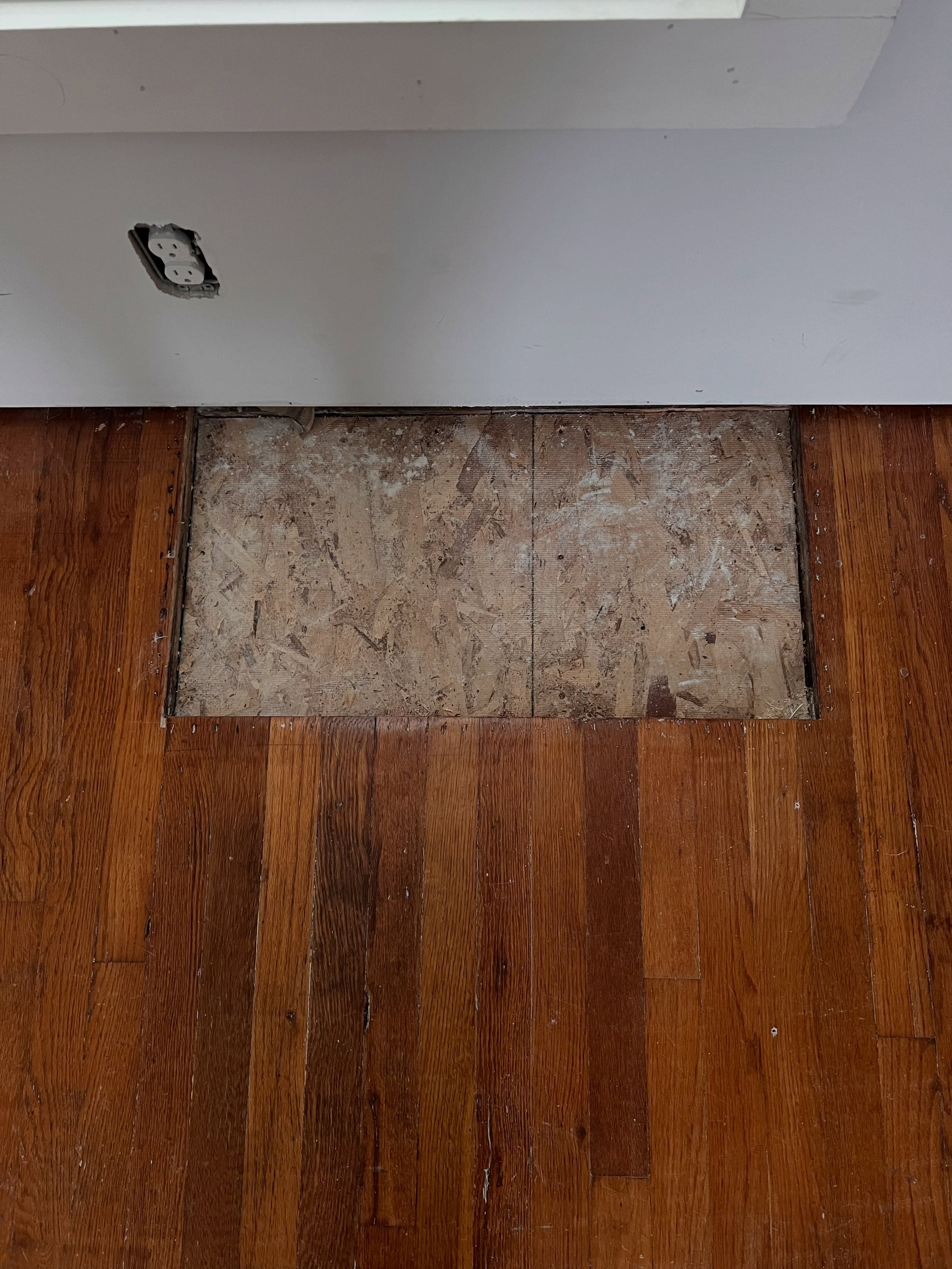 Flooring transition showing dark hardwood and light marble tile at junction