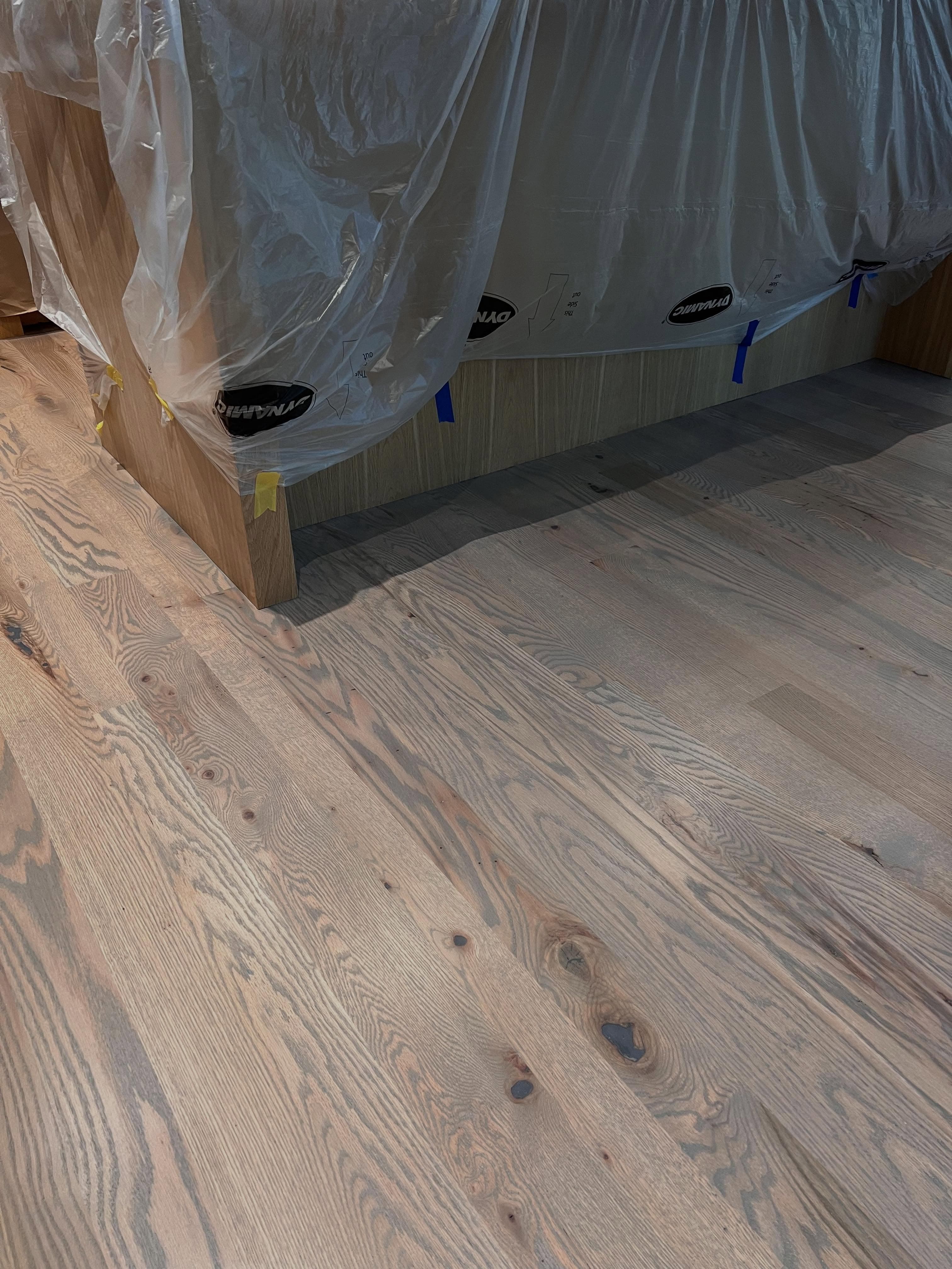 In-progress installation with new light wood planks and dust protection plastic