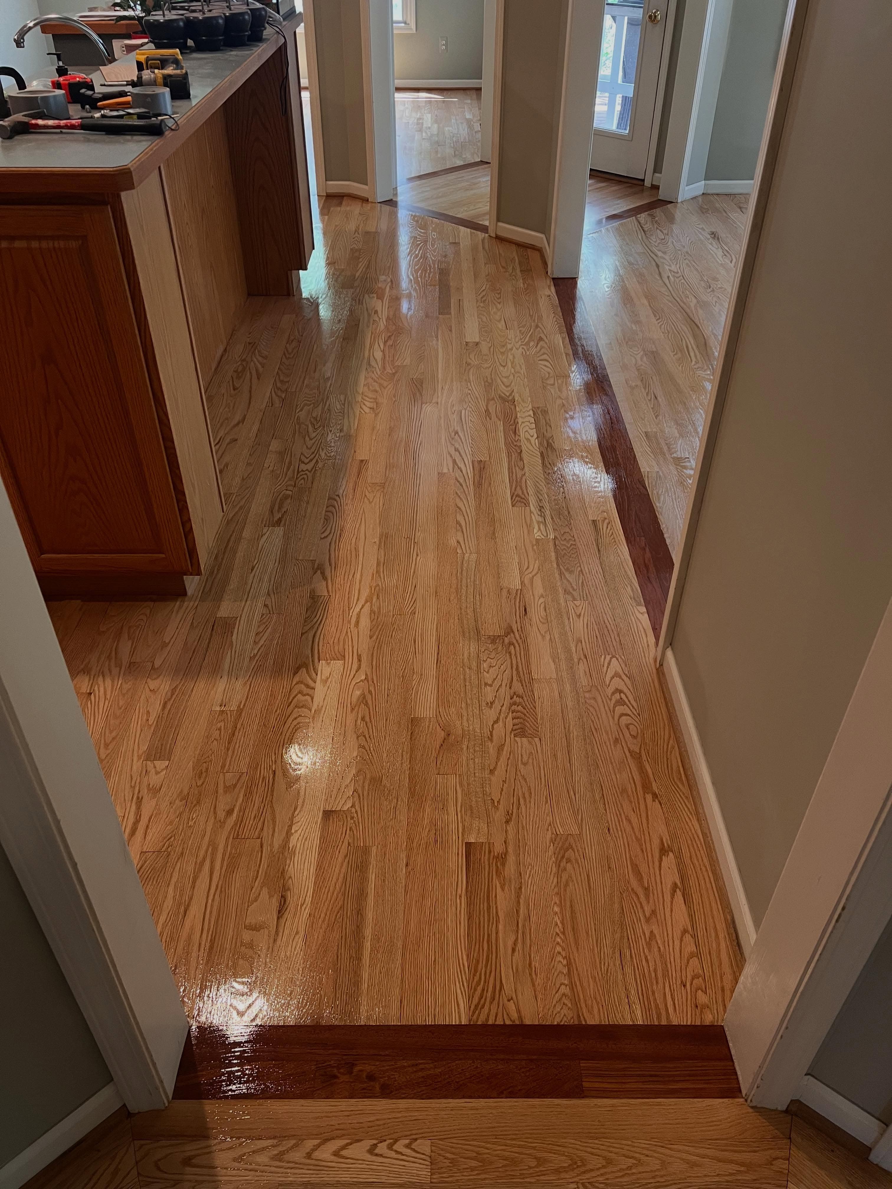 Hallway with glossy refinished hardwood flooring in warm tones