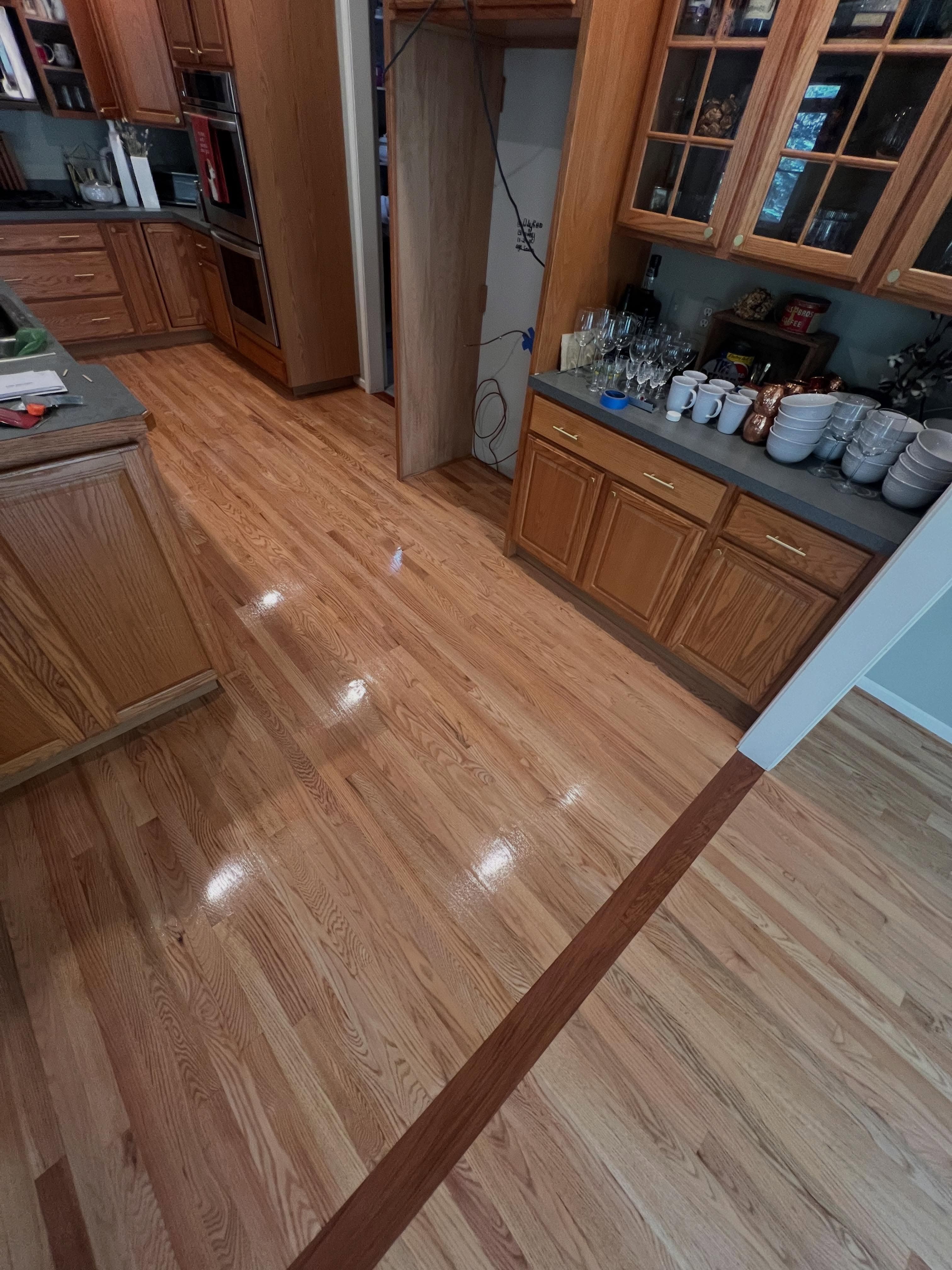 Kitchen and adjoining room with hardwood flooring in two tones, polished finish