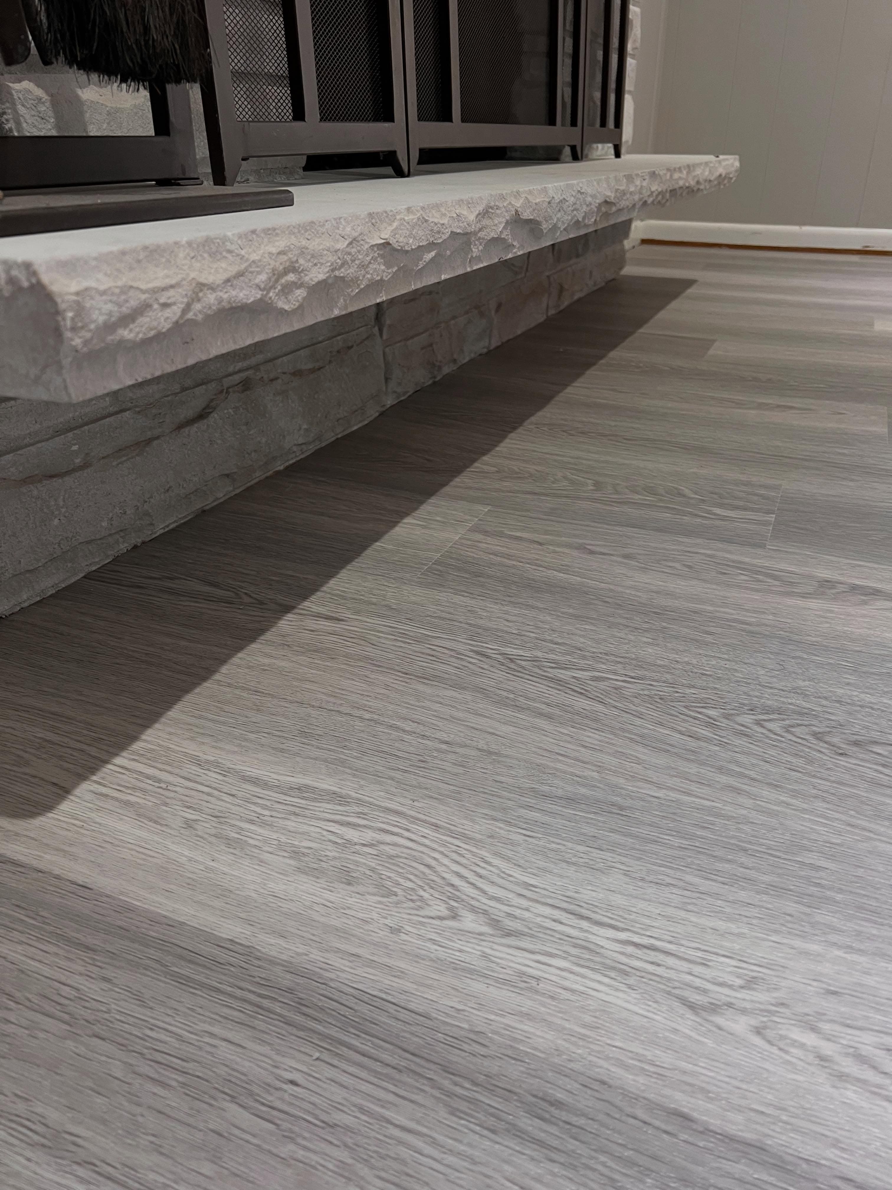 Light gray vinyl plank flooring next to textured stone element, modern style