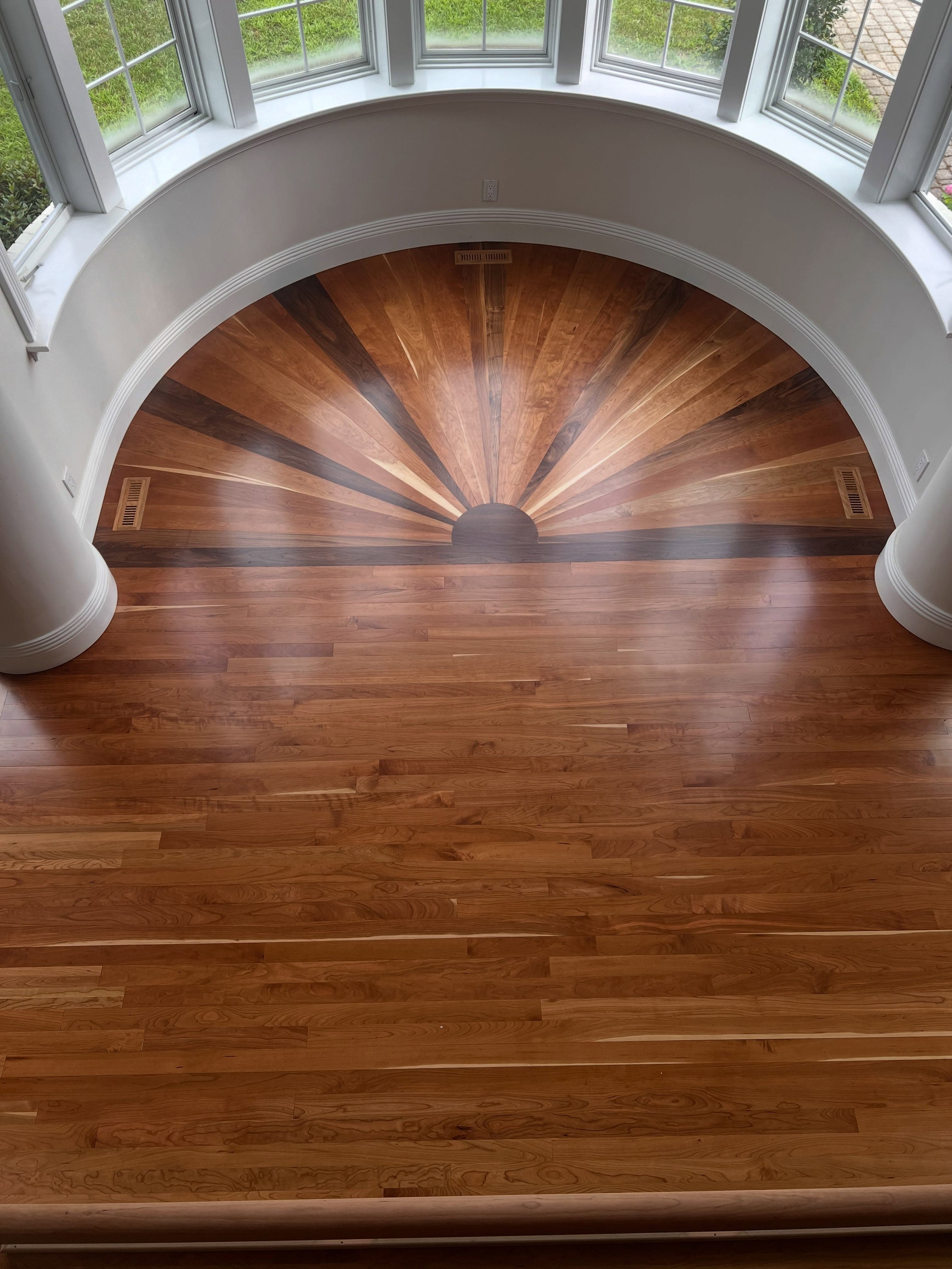 Dramatic hardwood flooring with radiant wood-grain pattern in a curved sunroom
