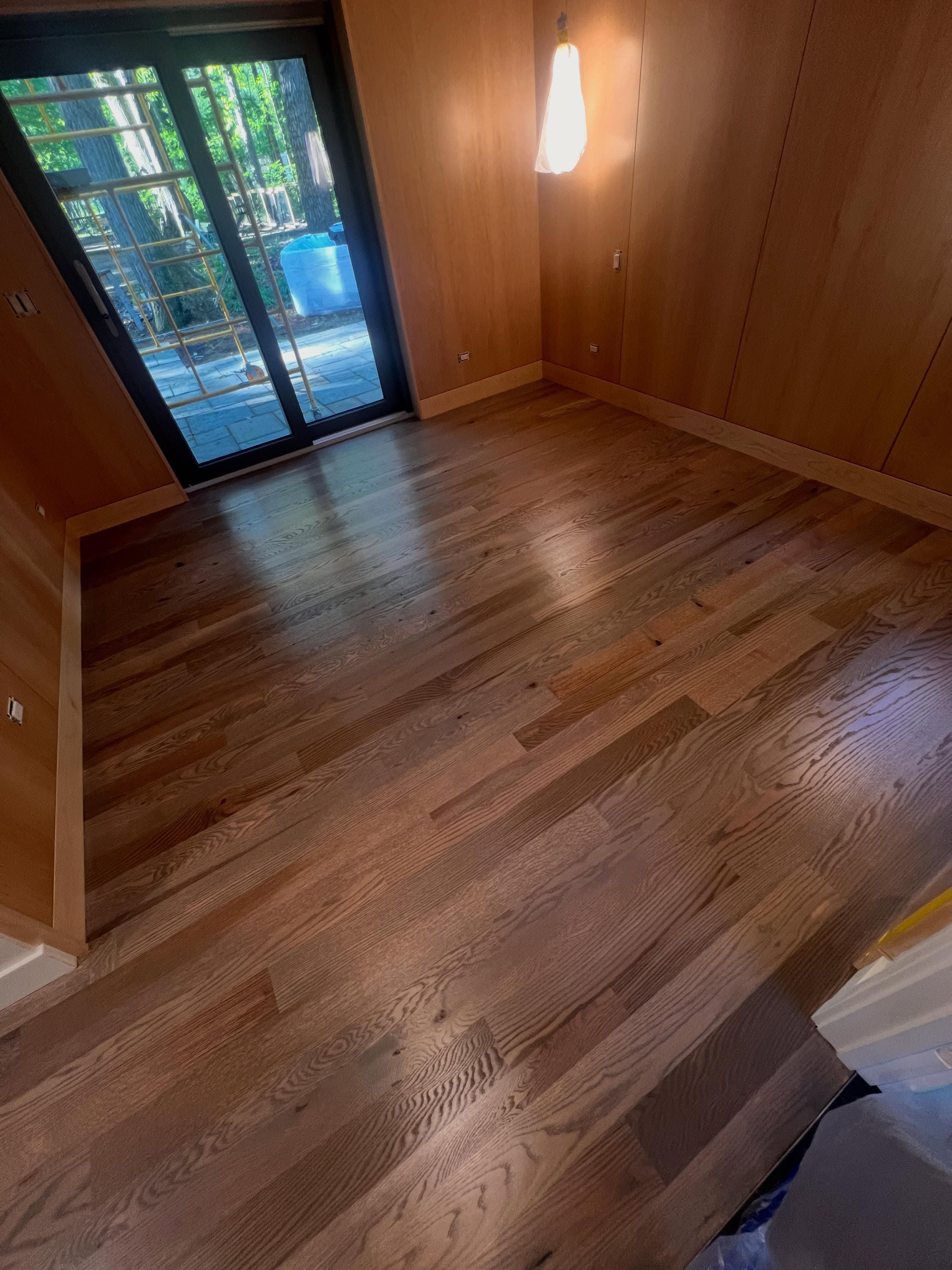 Wood-look flooring in a hallway with wood wall paneling and glass door