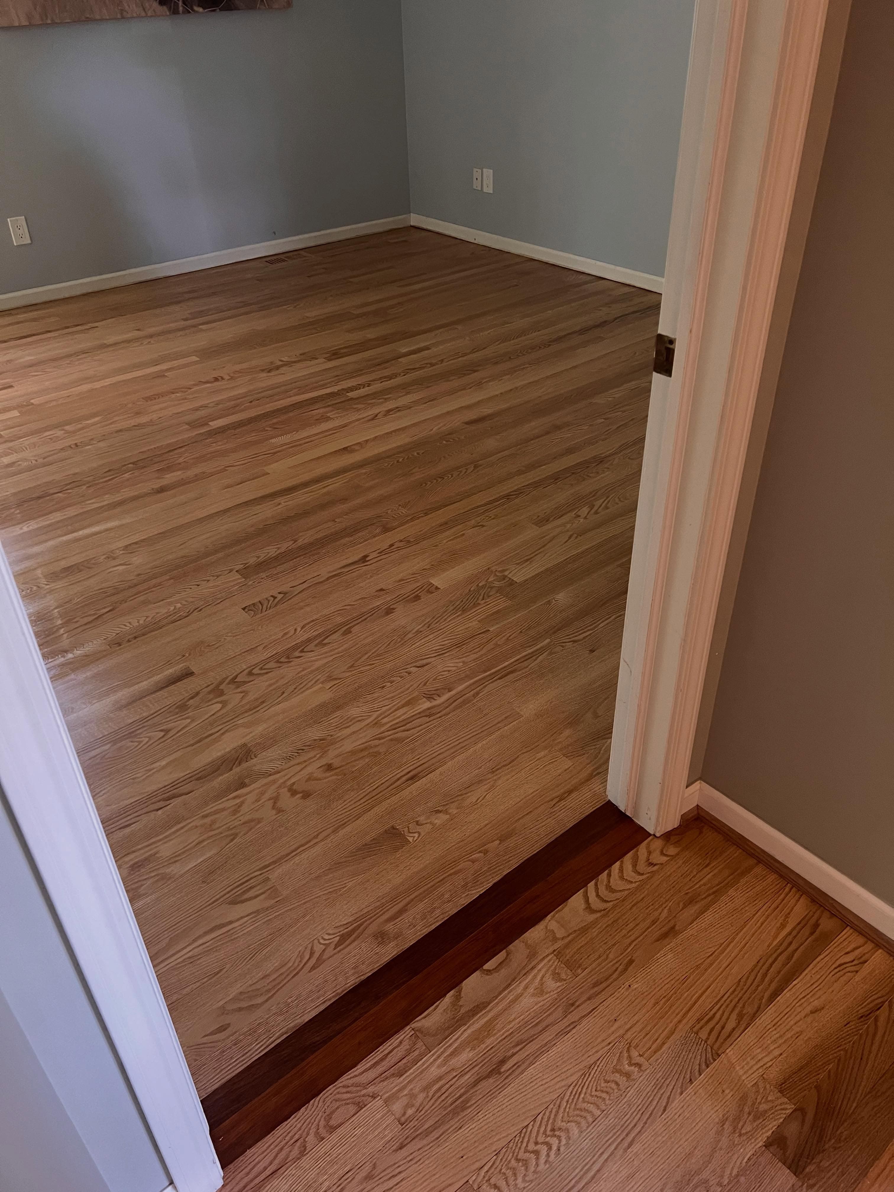 Transition between honey-toned laminate and darker wood, white trim