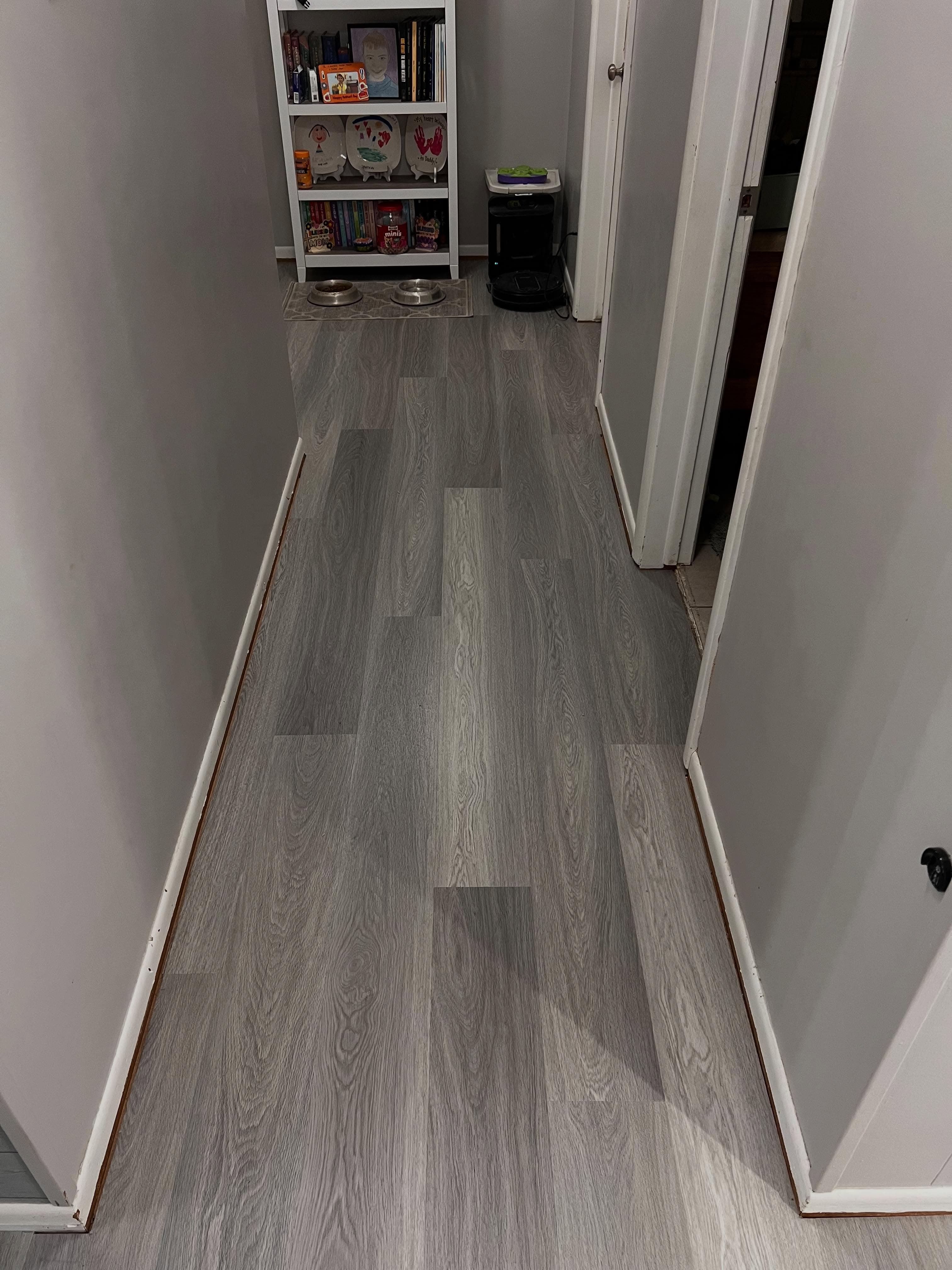Long corridor with gray wood-look vinyl plank flooring, white walls
