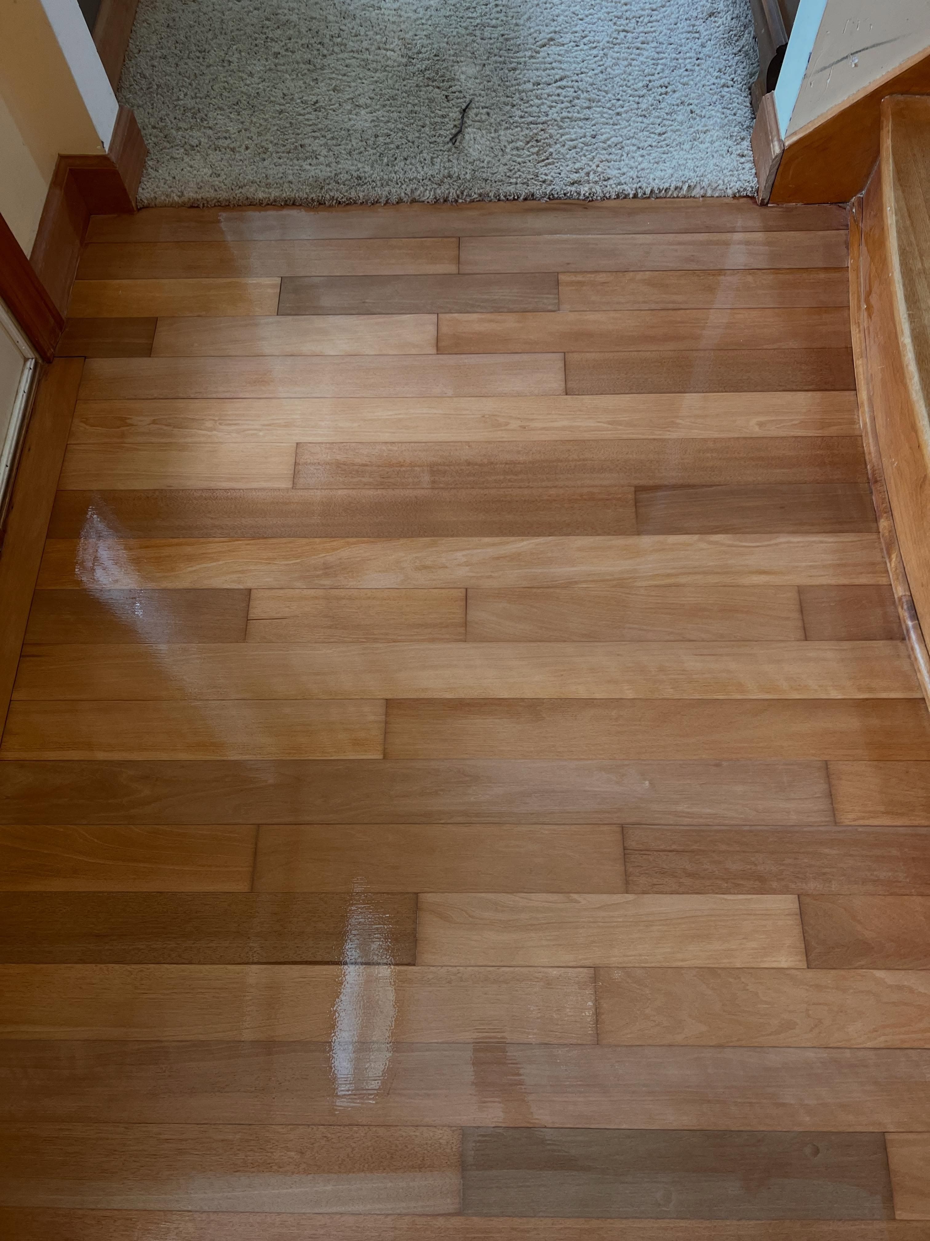 Hardwood floor installed at stair transition with polished wood grain and plank joints