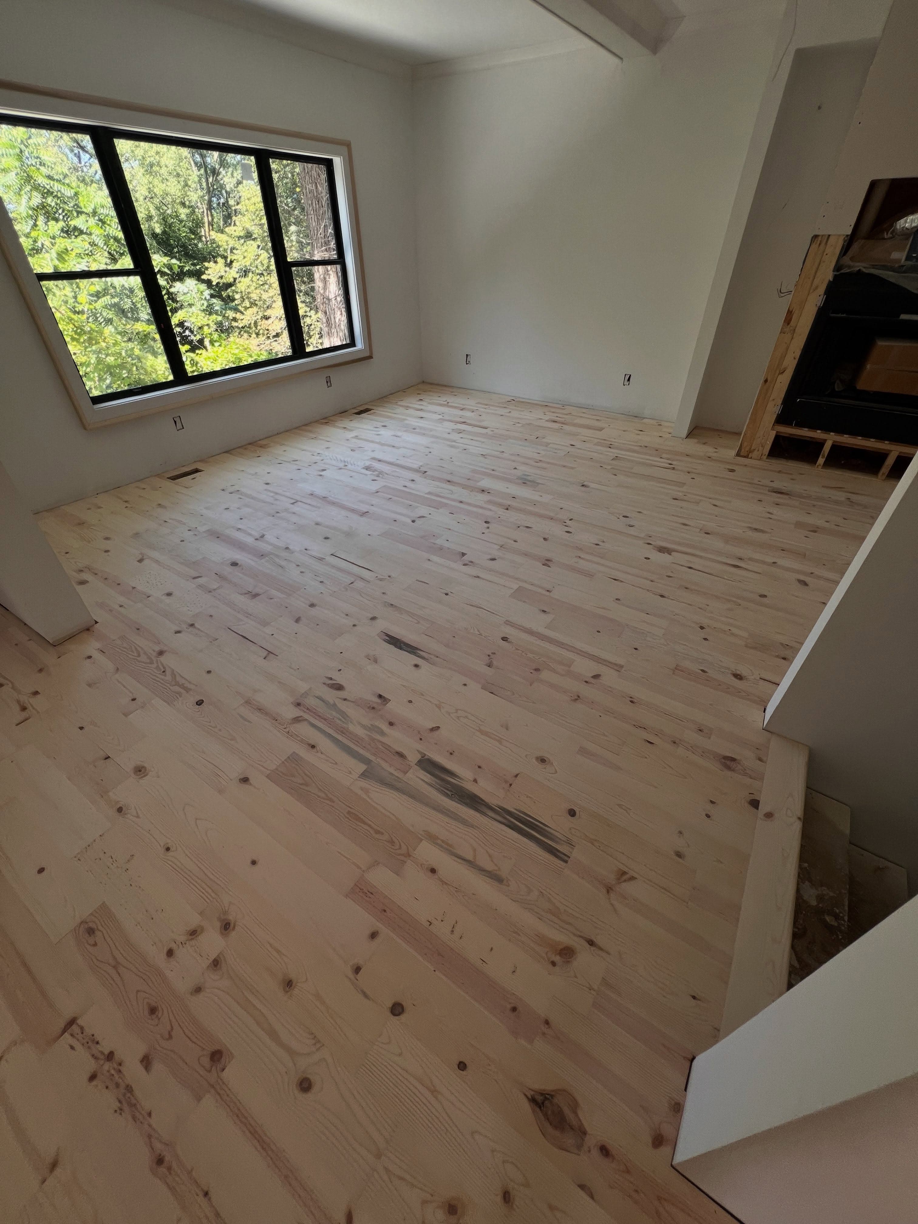 Empty room with newly installed light pine hardwood flooring, white drywall