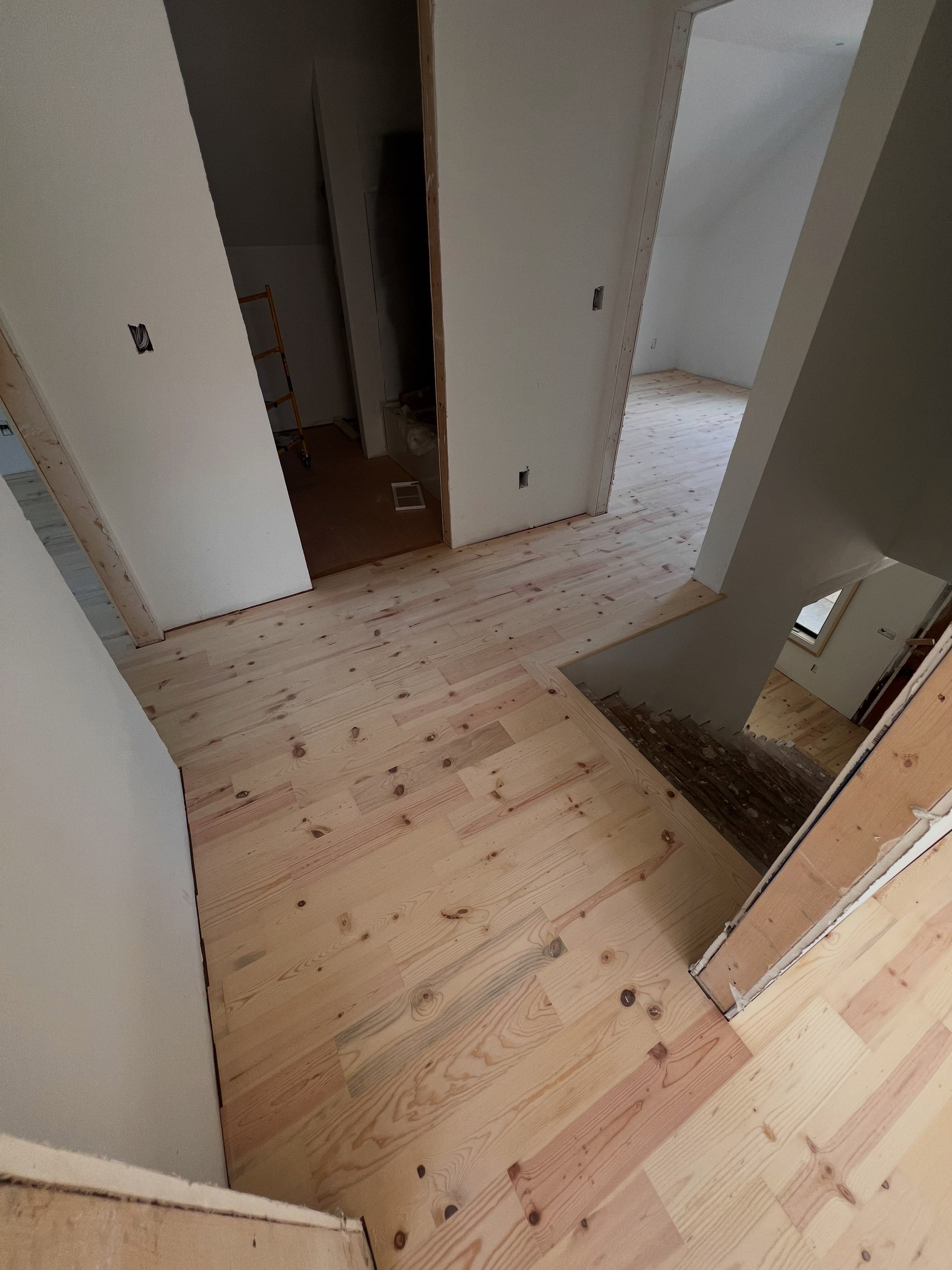 Hallway with newly installed light pine hardwood flooring, white drywall walls