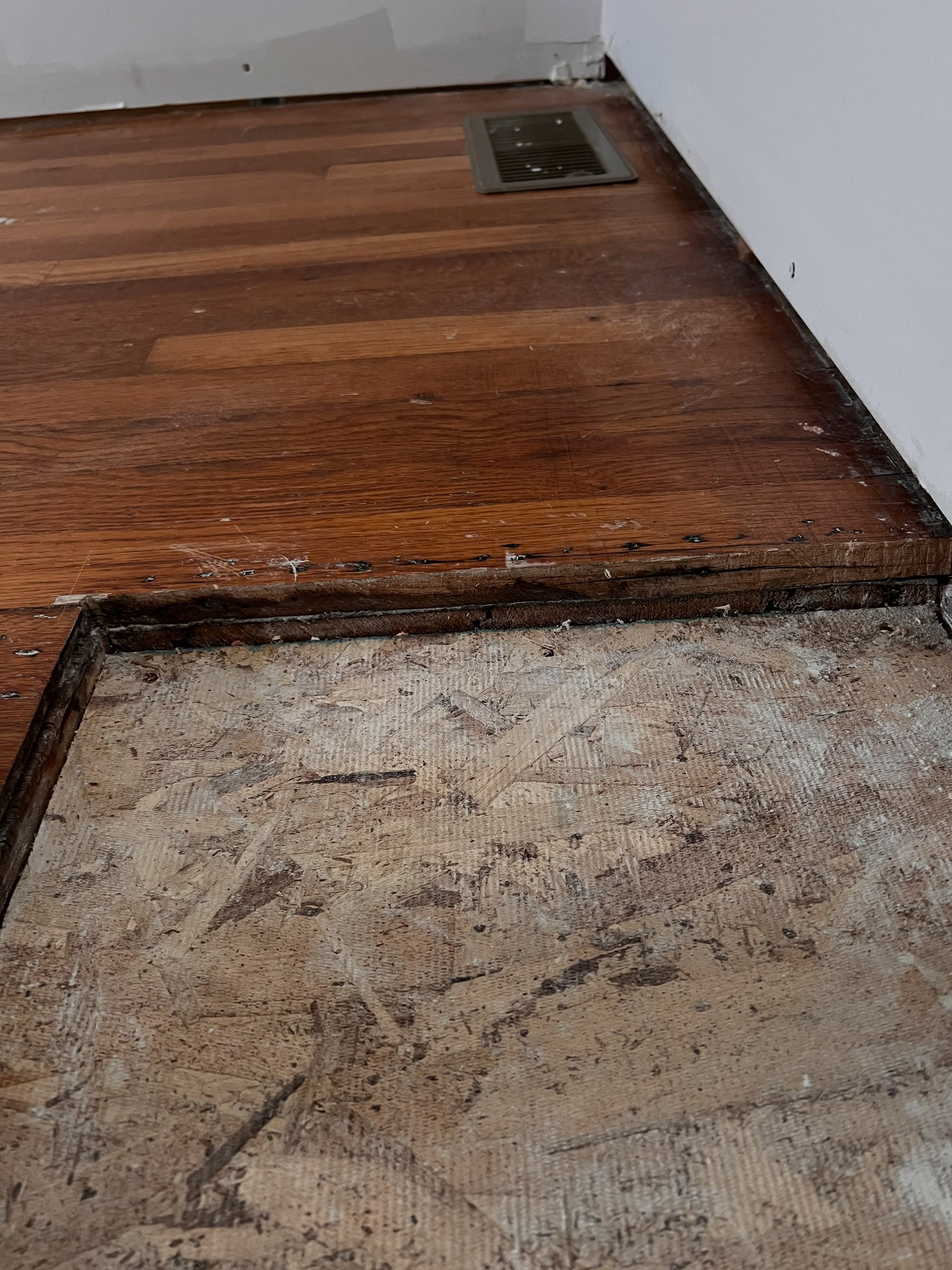 Flooring removal and replacement in progress, old dark hardwood being removed