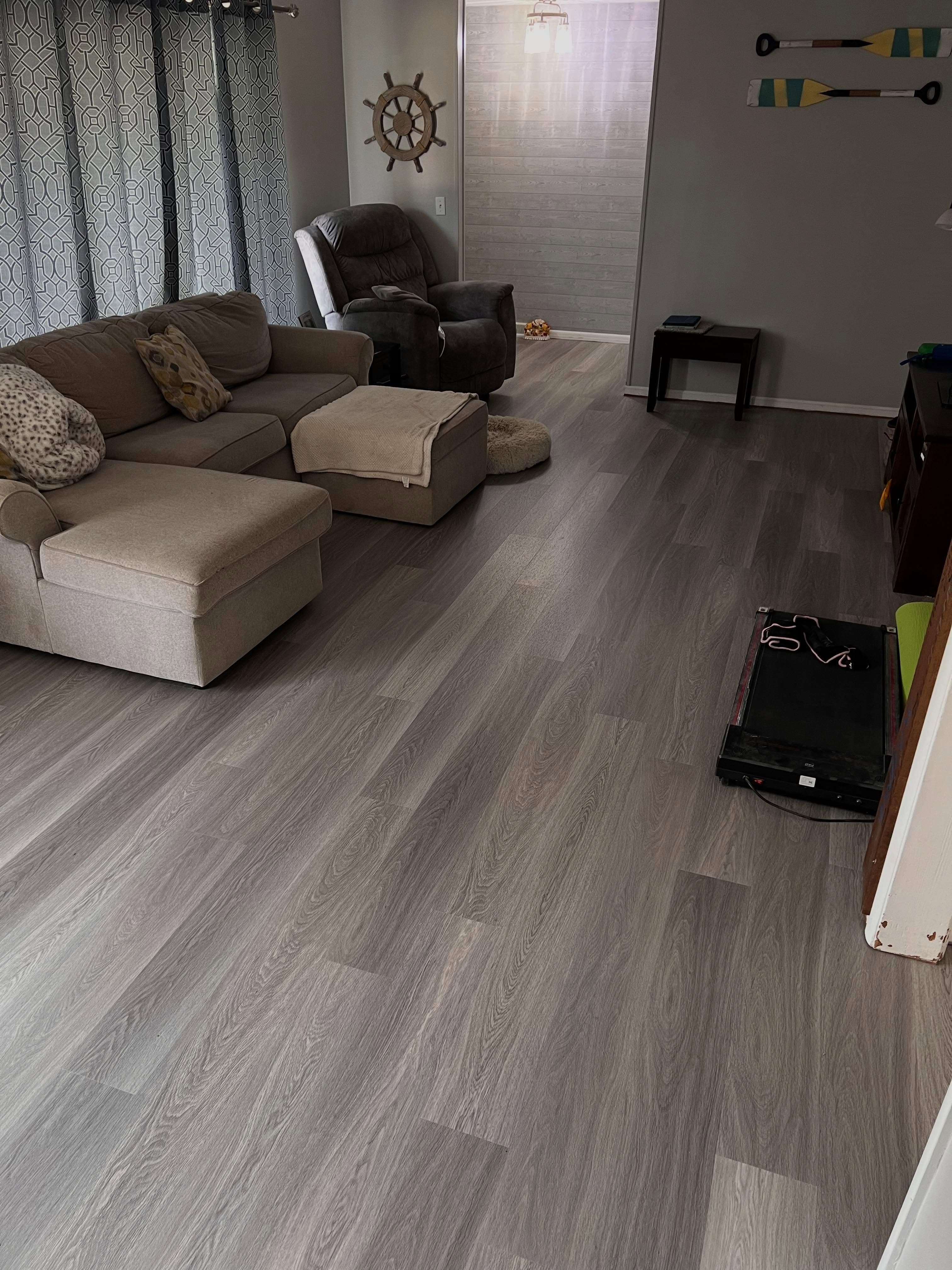 Living room with gray-tone wood plank flooring, beige sectional sofa
