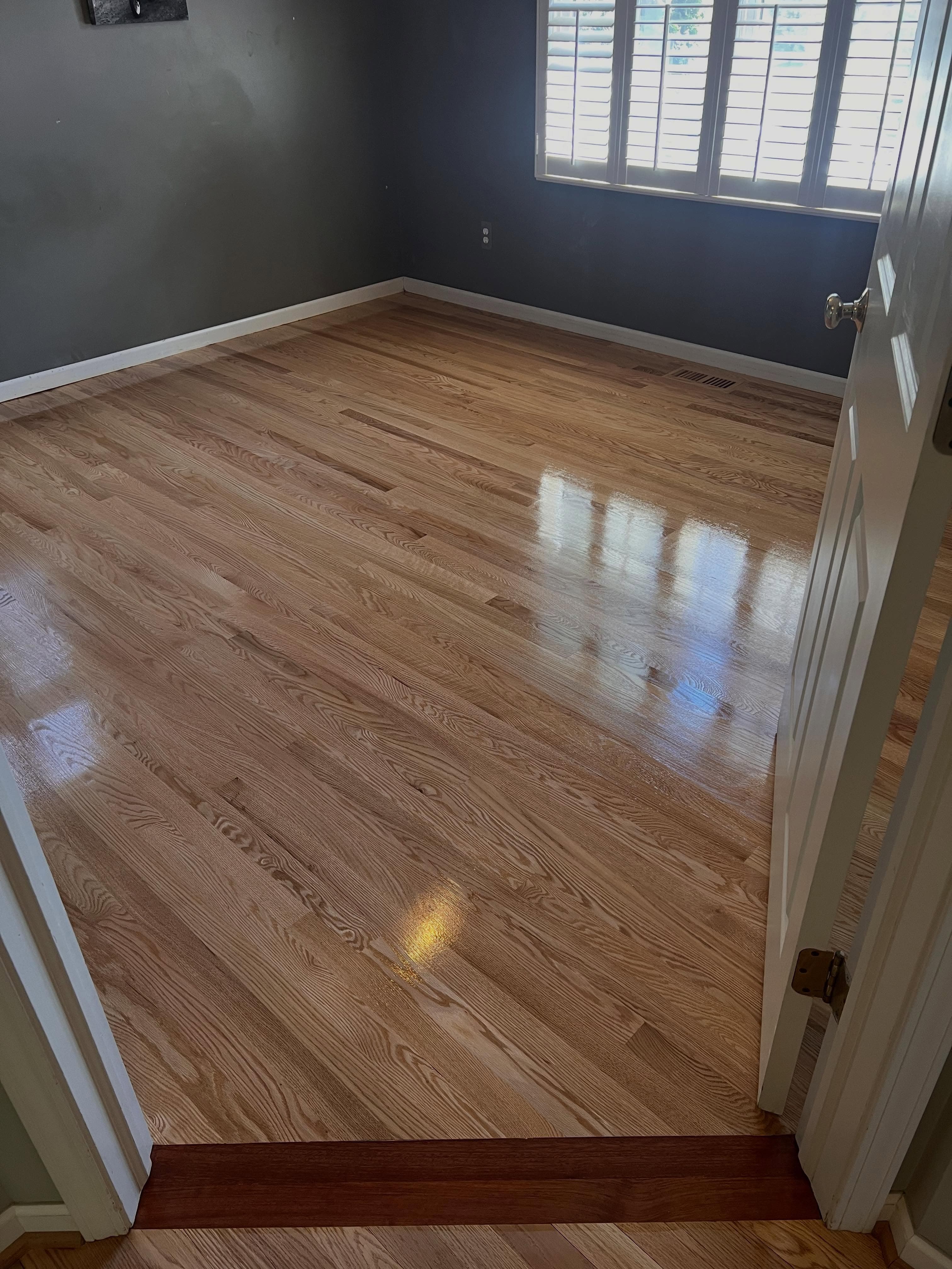 Empty room with refinished light oak hardwood flooring, two-tone walls